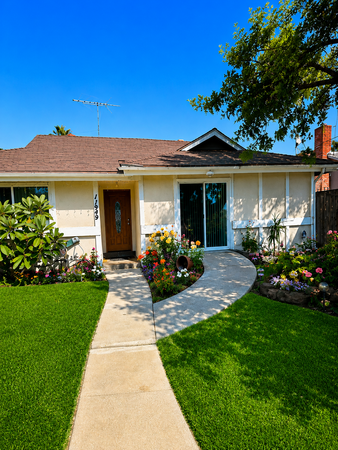 Front exterior of the residential care home with a curved walkway, green lawn and flower beds